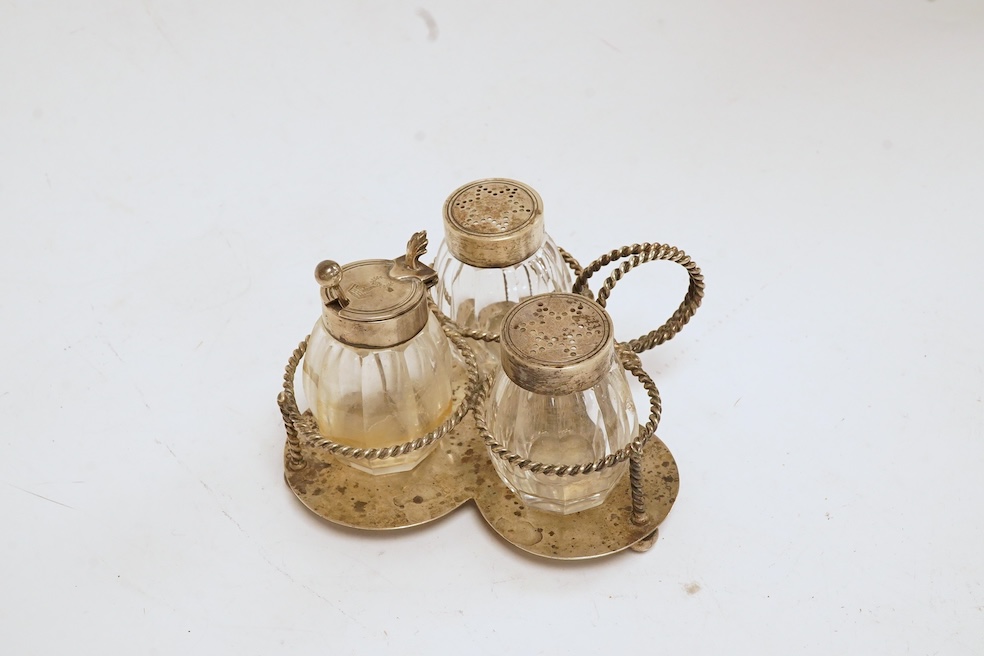 A late Victorian silver small cruet stand, with three mounted glass bottles, all Hukin & Heath, Birmingham, 1897, one associated bottle London, 1891, diameter 10.9cm, together with three assorted silver napkin rings, a s